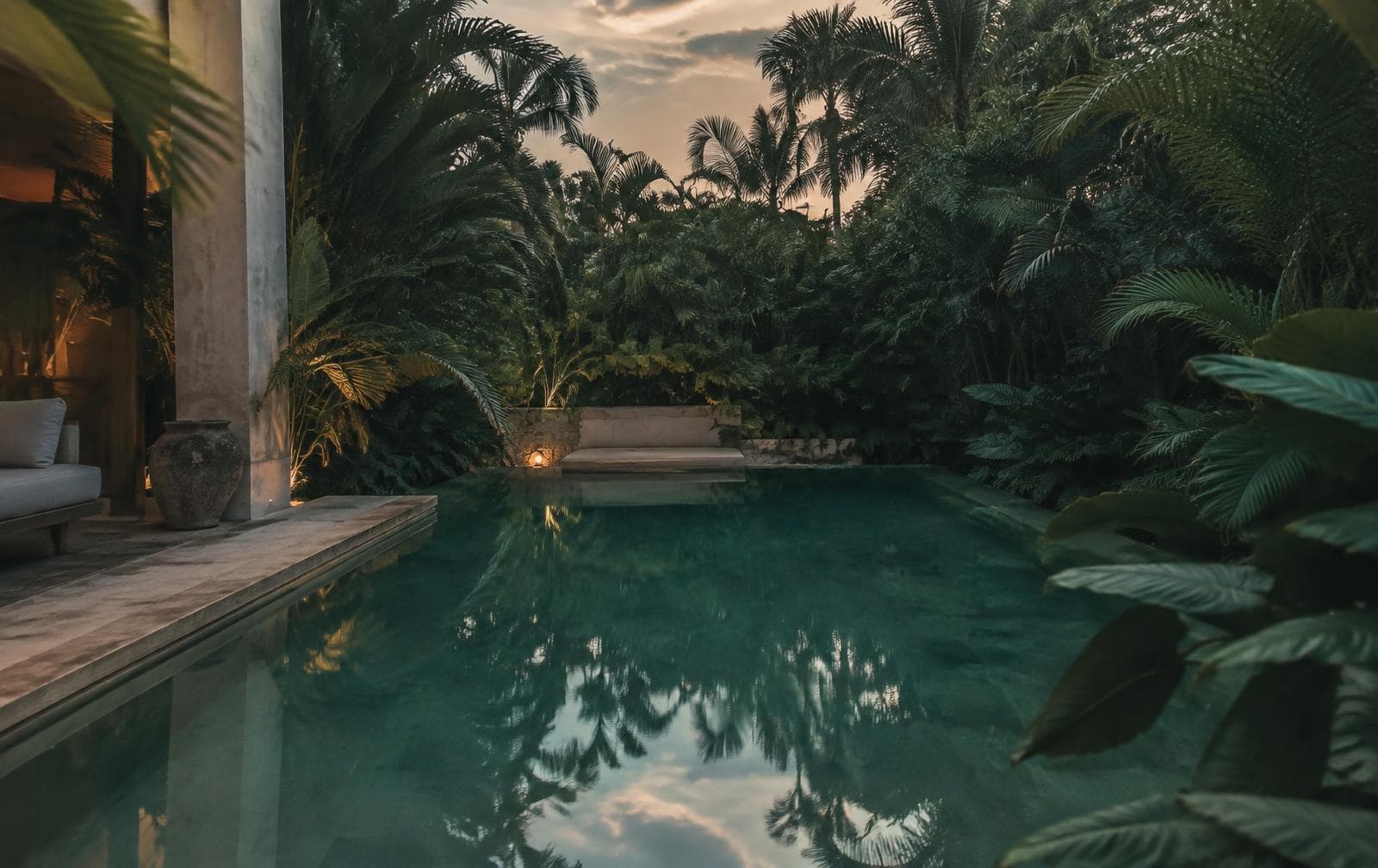 A private pool surrounded by lush greenery at dusk